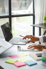 Fototapeta premium Young colleagues discuss business and analytical price charts using calculators and laptops to calculate financial, tax, accounting, statistics and analytical research ideas..