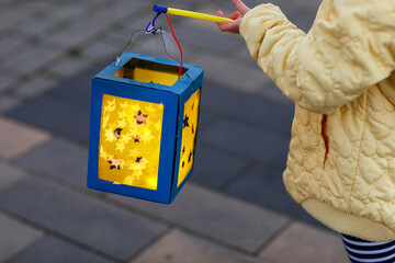 Closeup of little preschool kid girl holding selfmade traditional lanterns with candle for St....