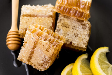 honeycomb and honey with fresh lemon on black background