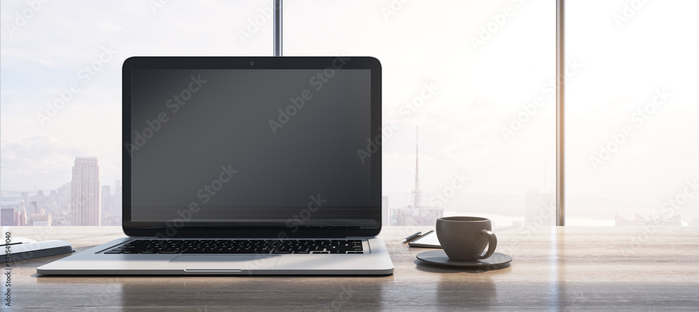 Aufkleber Wide image of laptop with empty mock up monitor, coffee cup and notepad placed on wooden desktop. Window with bright city view in the background. 3D Rendering.