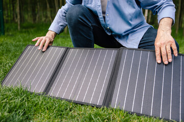 Man holding solar panel in garden.