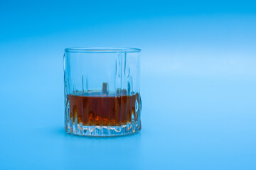 Izolowana szklanka do whisky z nalanym alkoholem na niebieskim tle