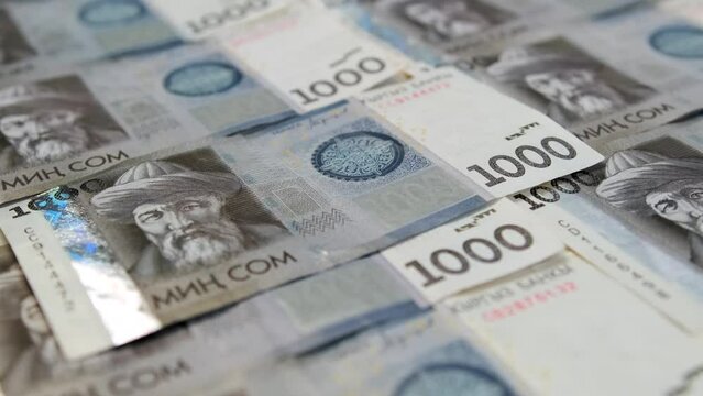 Many banknotes of 1000 Kyrgyz som neatly laid out cash on table. One  thousands som money business background. National currency Republic of Kyrgyzstan. Financial success and abundance.