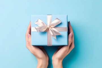 Female hands with natural manicure holding blue gift box with light golden ribbon on trendy beige background. Xmas and New Year postcard design. Black Friday sales, Birthday celebration party concept - 640556204