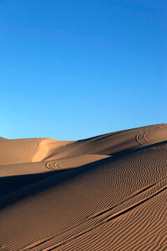 Sand dunes with wheel ruts and patterns in sand vertical
