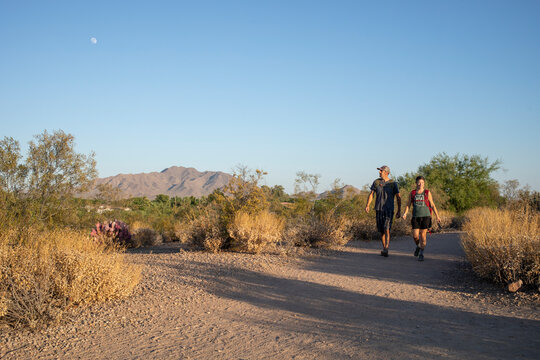 Couple hiking desert nature trail under day moon