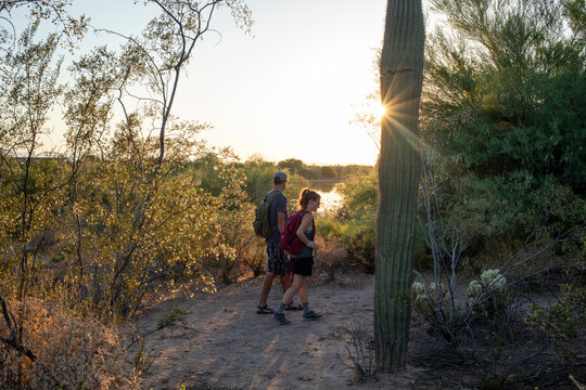 Couple hiking past saguaro cactus at sunset