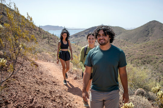 Three hikers on desert trail lake in background