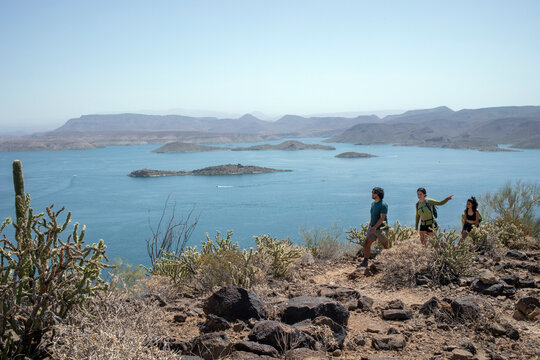 Hikers on desert mountain trail lake in background