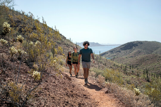 Hikers walking hilly path lake in background
