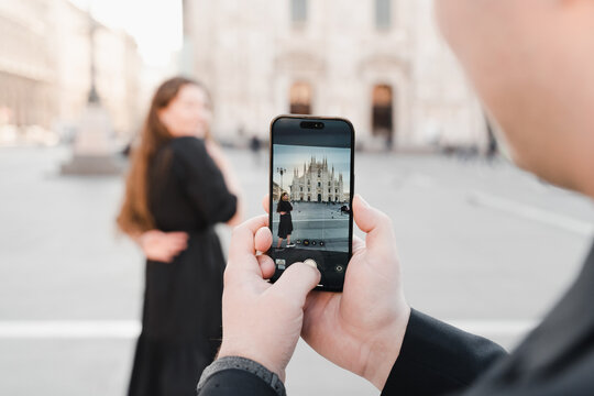 A couple in love take a photo on a smartphone in Duomo square, Milan