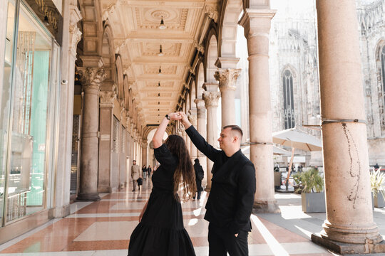 A loving couple in black dances in a gallery in the center of Milan