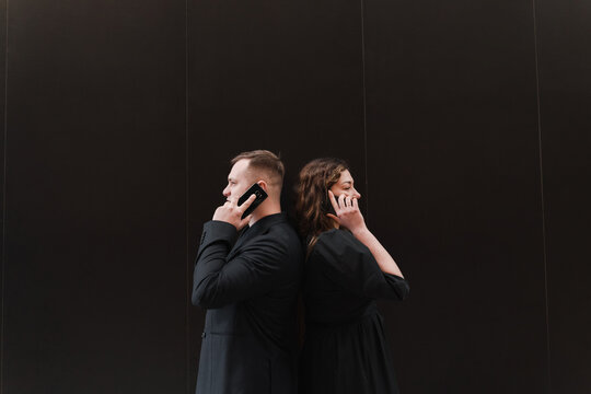 A girl and a guy speak on the phone in black on a black background