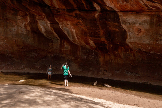 A young couple take photos under rock ledge
