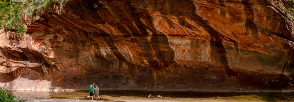 Panorama of young couple under large rock ledge