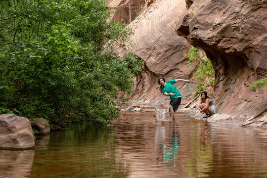 Young man skipping stones in stream