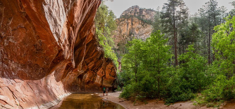 Young couple walking along stream under rock ledge