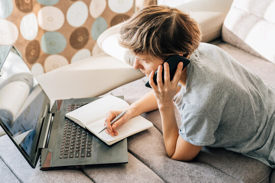 Short-haired blonde talks on a mobile phone while working from home