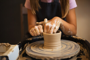 Close up of teenage girl's hands modeling pottery on a potter wh
