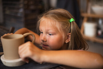 Portrait of girl working with ceramic clay in modern pottery wor