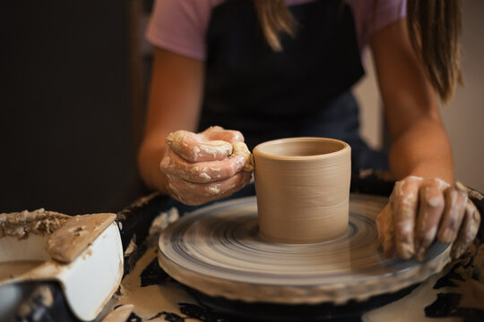 Close up of teenage girl's molds clay pot spinning on pottery wh