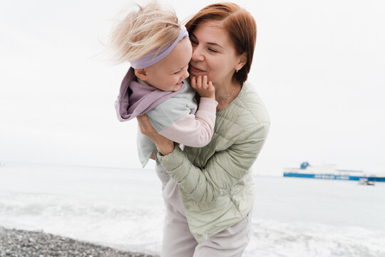 Red-haired woman smiles and fools around with her daughter 2 years old