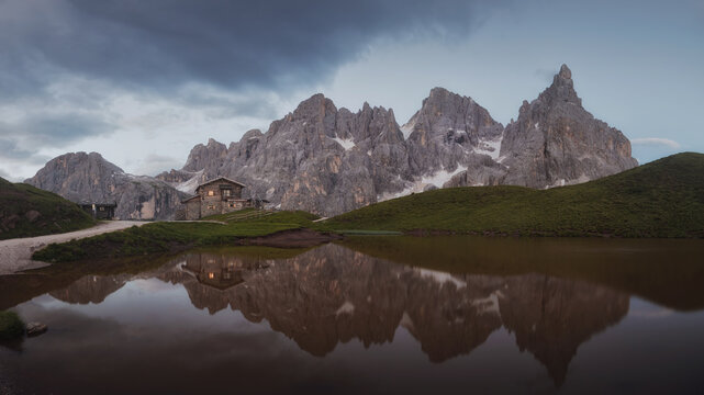 Baita Segantini reflecting in small lake. Italy, Dolomites, Trentino