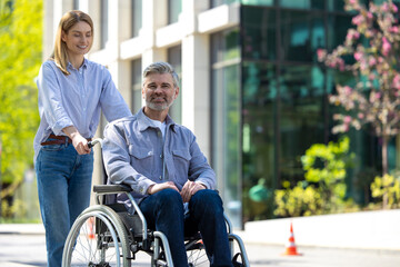 Man in wheelchair and woman walking in city street.