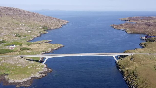 Wide angle drone shot of the bridge connecting the Isle of Scalpay to the Isle of Harris on the Outer Hebrides of Scotland. The town of Tarbert and the surrounding bay is visible.