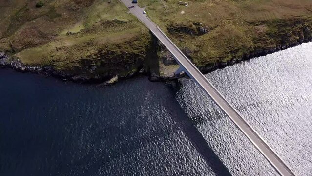 Dynamic drone shot tilting from the bridge to the village on the Isle of Scalpay, an island near the Isles of Harris and Lewis on the Outer Hebrides of Scotland. The Minch sea is visible.