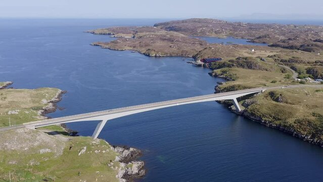 Advancing drone shot of the bridge connecting the Isle of Scalpay to the Isle of Harris on the Outer Hebrides of Scotland. The town of Tarbert and the surrounding bay is visible.