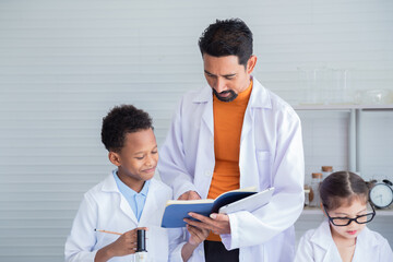 Fototapeta premium Adorable Multicultural school boy and girl students kids wearing lab coats happy study with Indian teacher sending experiment paperwork in laboratory room, lifestyle learning education science class