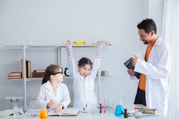 Indian teacher give thumbs up to Adorable sibling primary school student kids girl in science class for good experiment method using modern technology tablet application, lifestyle education learning