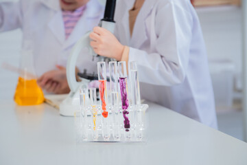 Fototapeta premium Unrecognizable close-up primary school boy student wearing lab coats happy studying with chemical teacher analyzing substance liquid test in laboratory room, lifestyle learning education science class