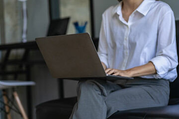 Side view of business woman's hands using laptop computer resting, young woman writing in blank notebook placed on office table with laptop keyboard close up pictures