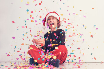 Obraz na płótnie Canvas Smiling boy in Santa hat under colorful confetti
