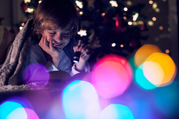 Positive boy reading book in dark illuminated room