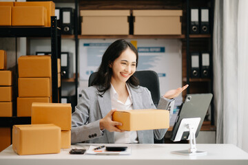 Beautiful Asian lady blogger showing clothes in front of the camera to recording vlog video live streaming at her shop. Online Shopping\