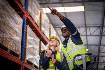 Obraz na płótnie Canvas Industry warehouse worker in safety uniform check order details and checking goods supplies on boxes shelve in workplace warehouse industry logistic export import distribution business concept.