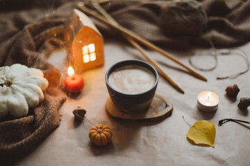 Fototapeta na wymiar Autumn cozy home interior with a cup, candles, plaid. Hygge home decor. Halloween and Thanksgiving concept 