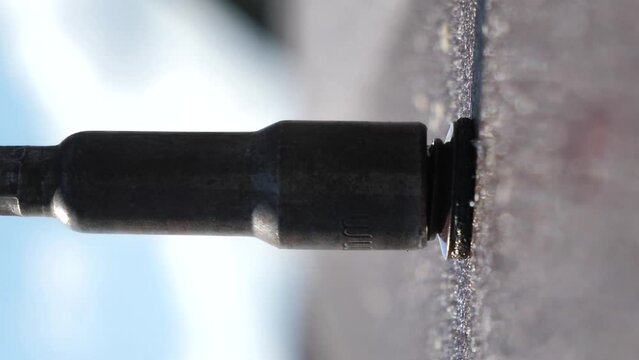 Screwing a roofing screw into a metal tile. Close-up of fastening a metal tile with screws. Roof installation.vertical video screen