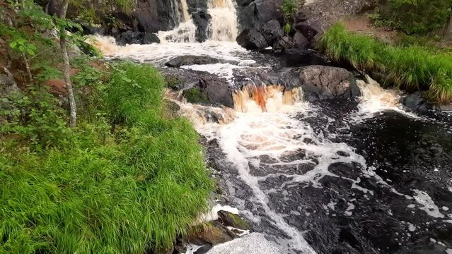 Beautiful waterfall among the stones in the green forest.