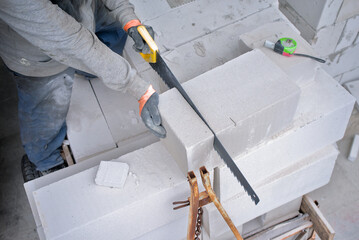 Builder sawing foam concrete for the construction of a new building