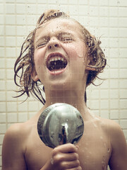 Little child singing with shower head as mic