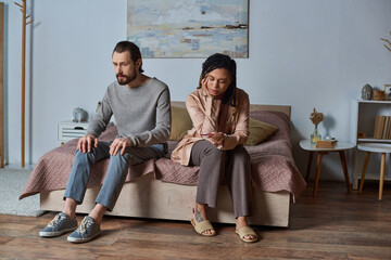 abortion concept, man sitting on bed, african american woman with pregnancy test, stressed couple