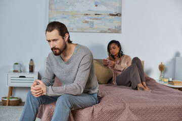 worried man sitting on bed, feeling stressed, african american woman with pregnancy test, decision