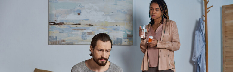 african american woman holding pills and glass of water, looking at stressed man, abortion, banner