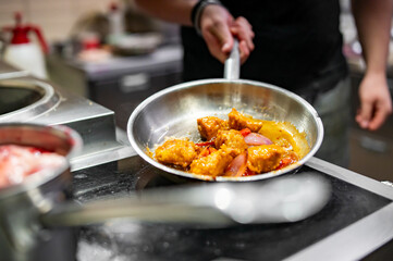 Chef cook hand cooking food in pan at the restaurant kitchen