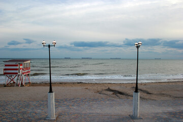 Fototapeta na wymiar Two lanterns stand on the sea coast against the background of clouds and the sea horizon