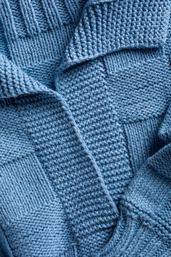Close up view of handemade knitted blue women jumper with polo collar. Stylish cotton pullover with chess texture pattern and long sleeves front view. Above shot
